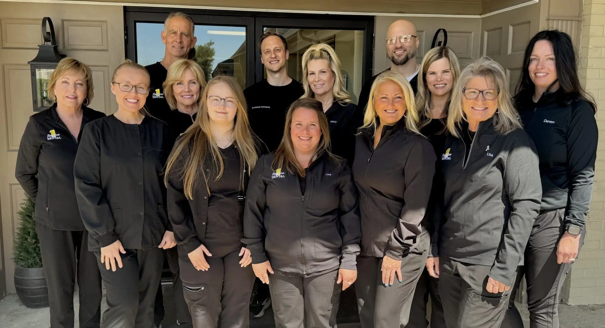 The First Care Dental team standing together in front of the 1005 office entrance in Louisville.