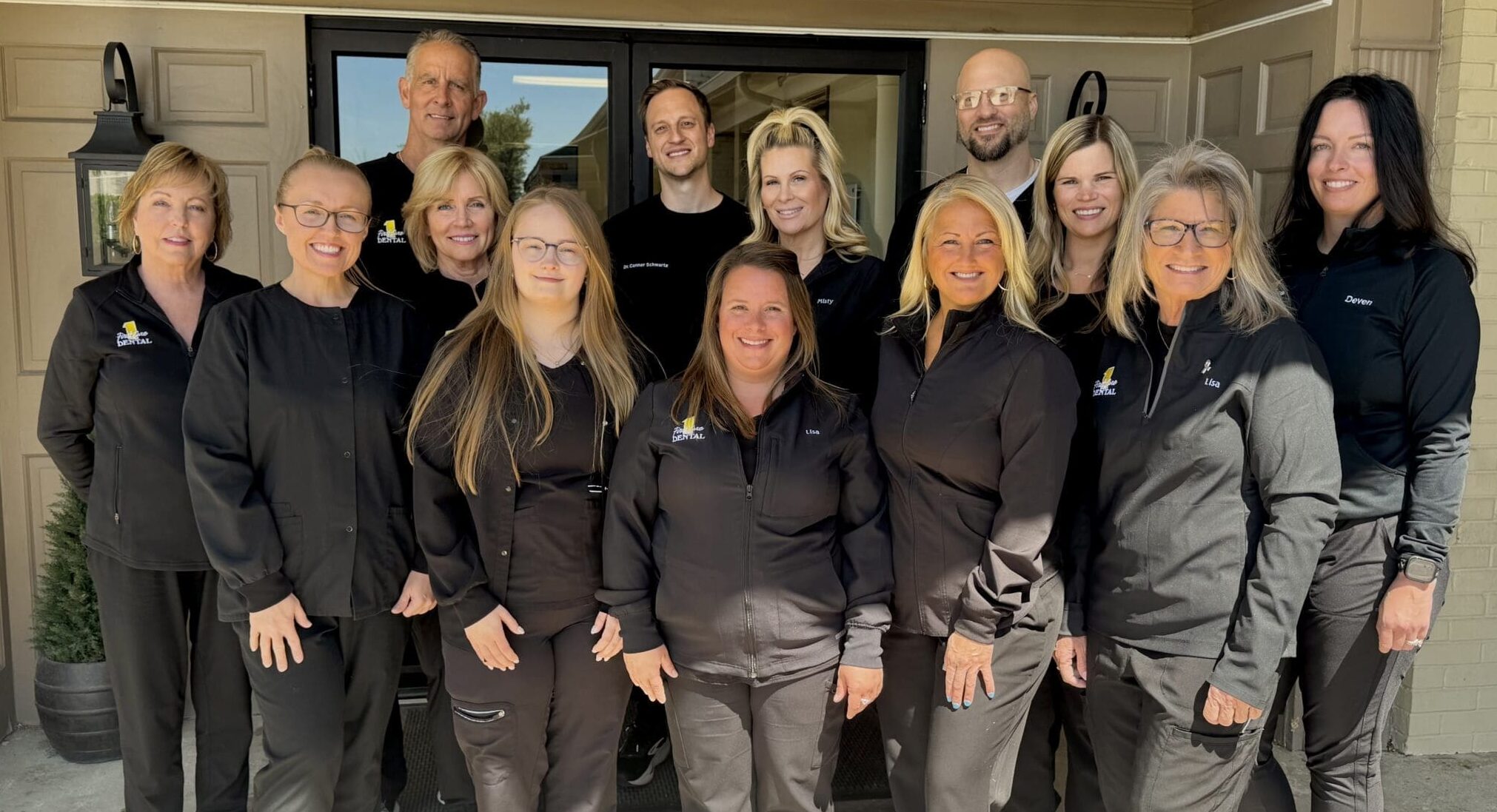 The First Care Dental team standing together in front of the 1005 office entrance in Louisville.